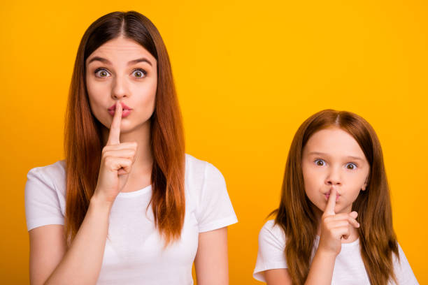 foto ravvicinata di persone carine con lunghi capelli di zenzero che dicono silenzio indossando maglietta bianca isolata su sfondo giallo - top secret foto e immagini stock