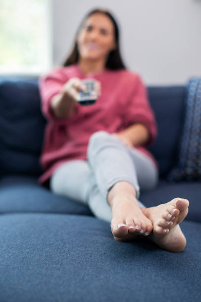 istock Woman Relaxing On Sofa Holding Remote Control And Watching Television 1172718852