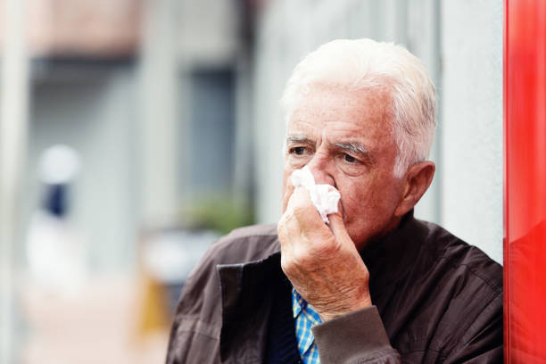 istock Senior man ill with flu blows his nose on a tissue 1172720530