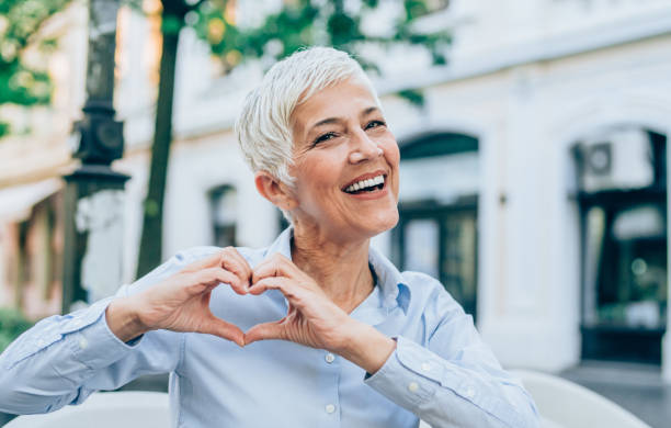 Portrait of a smiling mature woman Beautiful smiling mature woman making heart shape with fingers. eastern european 50s mature women beauty stock pictures, royalty-free photos & images