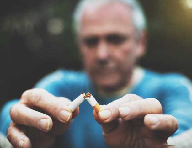 Senior man breaks his last cigarette as he gives up smoking Man is determined to stop smoking. last stock pictures, royalty-free photos & images