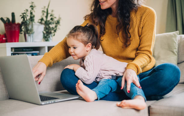 istock Mother and daughter using laptop on sofa 1172722036