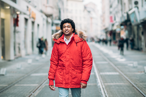 Young african american man with red jacket walking on the street