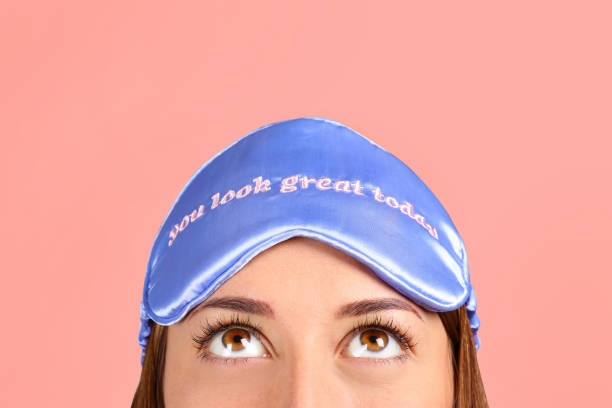 istock Smiling woman wearing blue sleeping patch on pink background. 1172723658