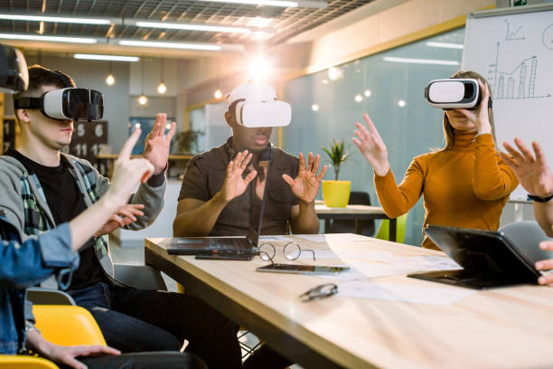 istock Multiracial best friends having fun wearing virtual reality glasses in creative office. Young people using new technology 1172723842