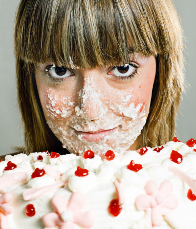 Nice girl with cream in the face from a pie.