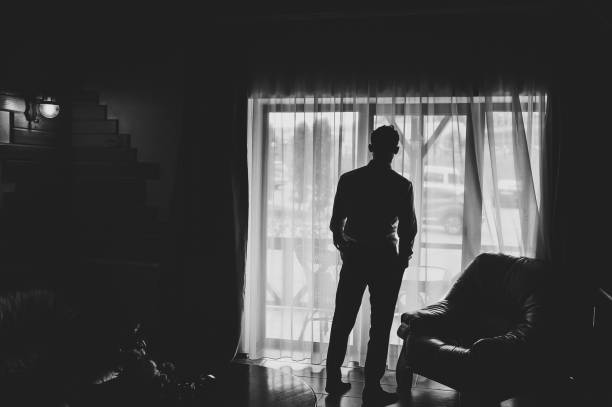 istock Silhouette man looking out the window. Black and white photo. Back view. 1172726199
