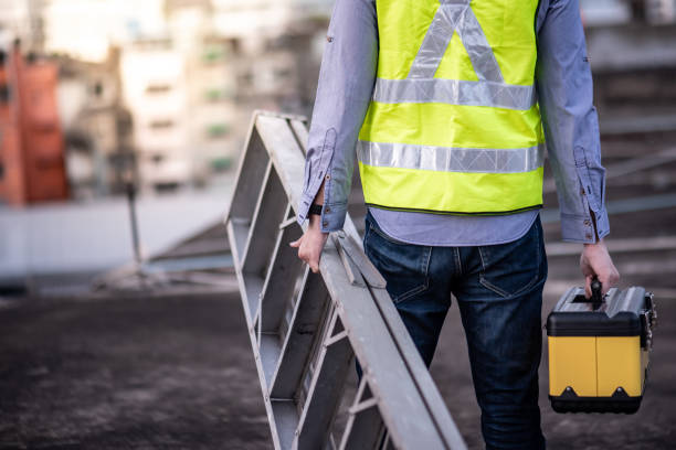 Worker man carrying aluminium ladder and tool box