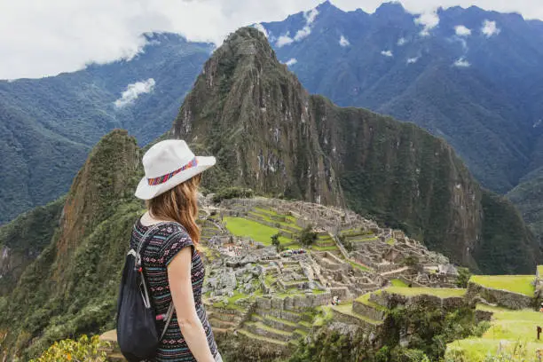 Photo of Young caucasian happy woman in Machu Picchu mountain and looking away in Peru. Back view with copy space