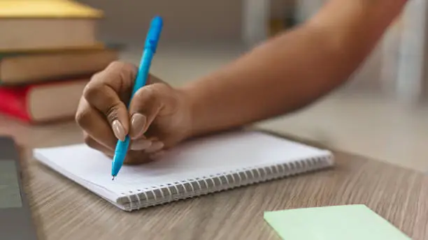 Photo of Teen black girl writing notes in notebook