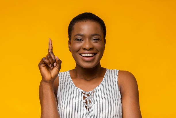 istock Playful young black woman pointing up on studio background 1172744672