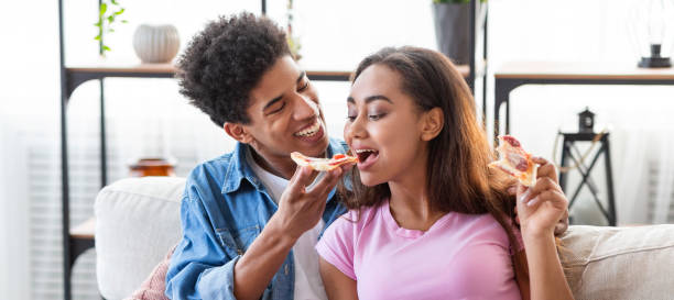 istock Black teenage guy feeding his girlfriend with pizza 1172747432