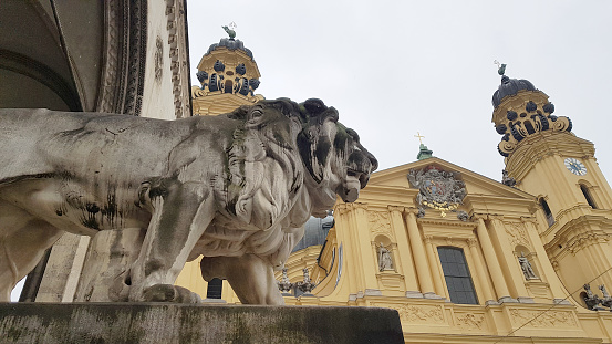 Theatinerkirche (Theatine Church of St. Cajetan) and the lion at the Feldherrnhalle in Odeonsplatz, Munich, Germany