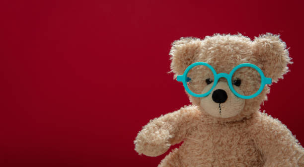 istock Cute teddy wearing eyeglasses against red background 1172750374