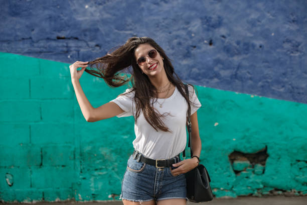 istock Happy female standing by wall pulling hair 1172756917