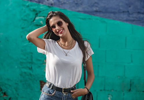 Happy stylish female standing by colorful wall