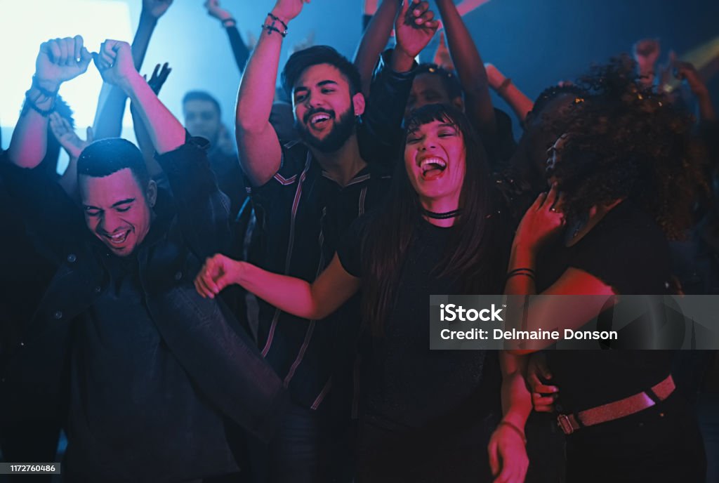 This is how we do! Cropped shot of a group of energetic young friends dancing at a party in a nightclub Party - Social Event Stock Photo
