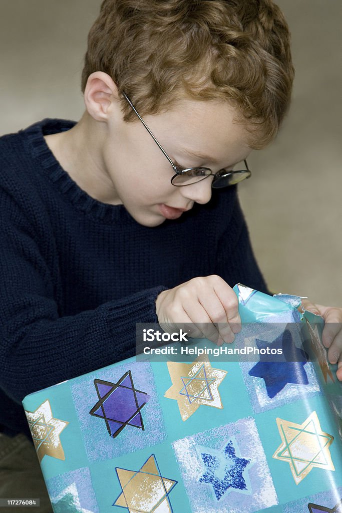 Hanukkah Young boy opening Hanukkah present. Hanukkah Stock Photo