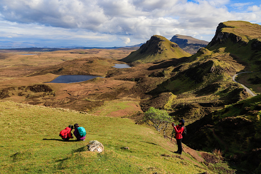 The Quiraing is one of the most attractive travel destination in Scotland.  It is located in the Isle of Skye, Scotland.  It's a unique place many people have always dreamed of going. This image shows happy family enjoying its stunning view.