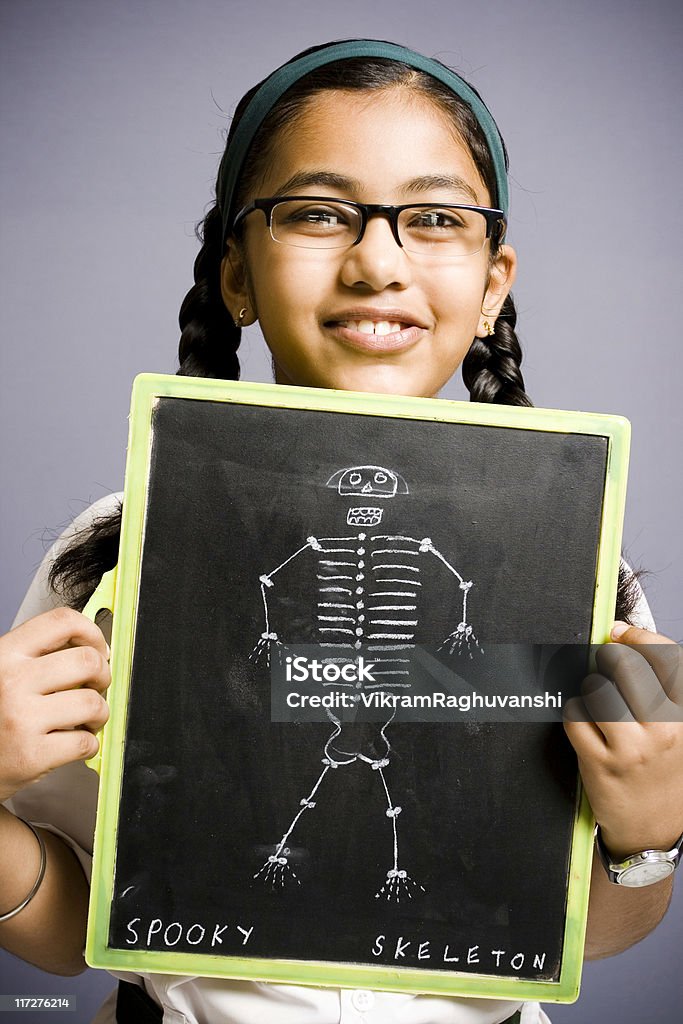 Allegro indiano ragazza di scuola con lavagna con il disegno di uno scheletro - Foto stock royalty-free di Bambine femmine
