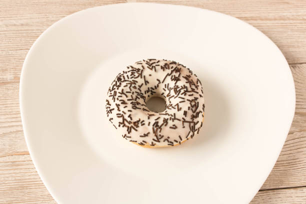 istock Fresh glazed donut with chocolate sprinkles on a white plate. 1172762396