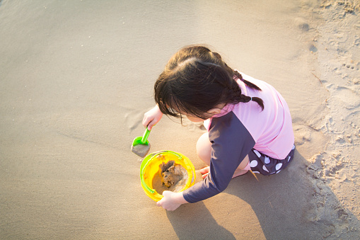 Little girl playing with sand on beach