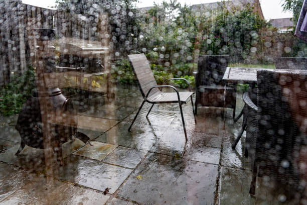 Back garden viewed through a patio door on a rainy day. It is a typical English summer's day with a rain storm passing through and leaving water droplet trails on the Patio door window.