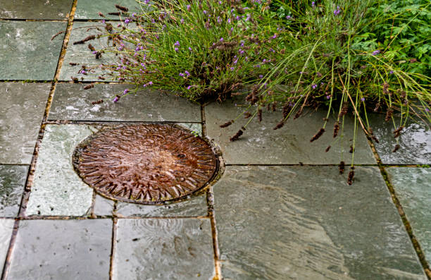 Back garden patio with a man hole cover on a rainy day. It is a typical English summer's day with a rain storm passing through and leaving water droplets on the Patio.