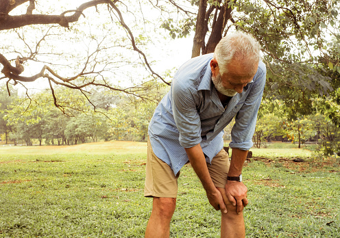 Aging man having pain in his knee on the park, Pain In The Elderly, Health care