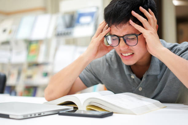 istock close up young asian man getting serious feeling after reading books for midterm or final test at library and using hand massage for relief and treatment symptom , healthcare lifestyle people concept 1172770341