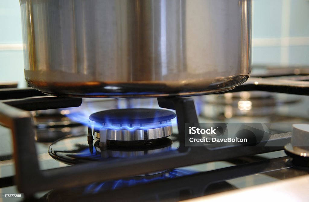 Gas Cooking Pan on a gas hob. Limited depthy of field with focus on igniter to left of burner. Abstract Stock Photo