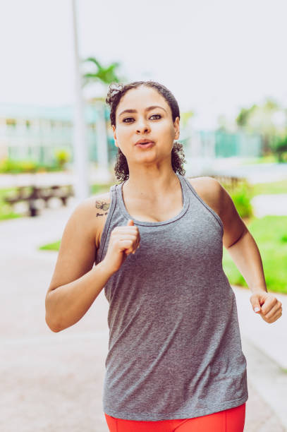 istock Attractive African american woman runs or jogs outdoors in workout gear 1172775174