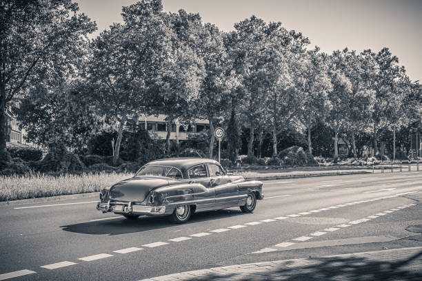 Black and white monochrome photo of an american oldtimer car from the 1950s. Vintage USA car on the street on a sunny summer day. Retro travel, traffic concept. - fotografia de stock