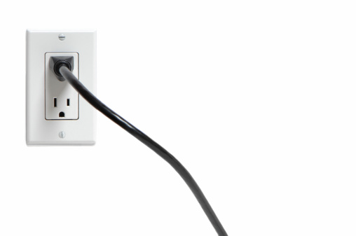 Black electrical cord plugged into outlet