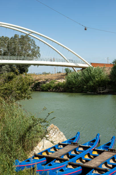 Canoes anchored at harbour on green river with bridge
