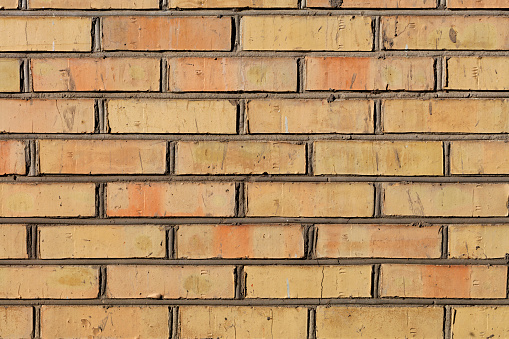 The old brick wall have an orange color and a weathered texture with cement jointing.