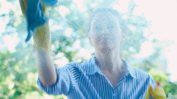 istock smiling lady in shirt sprays detergent on window and wipes 1172790377