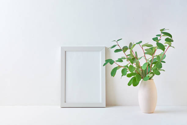 istock Mockup with a white frame and branches with green leaves in a vase on a light background 1172794678