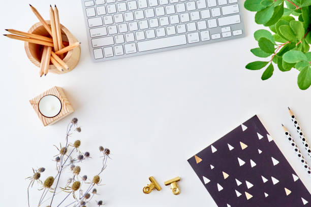 Blogger or freelancer workspace with keyboard, notebook and branches with green leaves on light background
