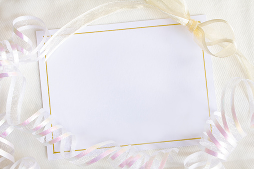 A blank card with white copy space, surrounded with elegant ribbons and a bow.