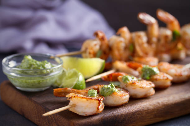 camarones salteados con salsa de mantequilla de ajo servidos con cilantro y lima en la tabla de servir - prepared shrimp skewer rice prepared fish fotografías e imágenes de stock