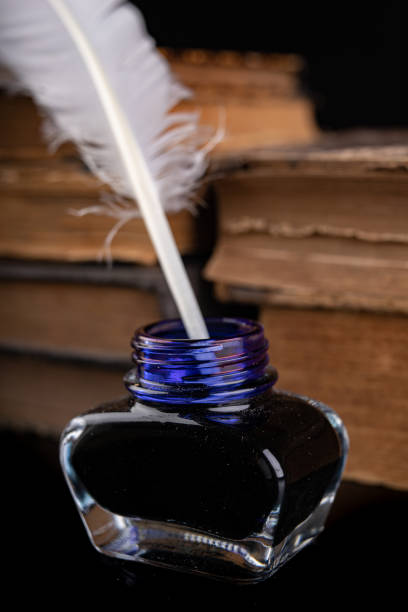 istock Old white writing pen in an inkwell. Calligraphy accessories on an old table. Dark background. 1172804970