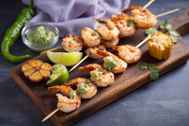 camarones salteados con salsa de mantequilla de ajo servidos con cilantro y lima en la tabla de servir - prepared shrimp skewer rice prepared fish fotografías e imágenes de stock