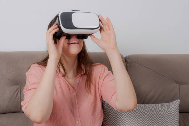 istock Woman using VR sitting on couch holding handset in both hands 1172806883