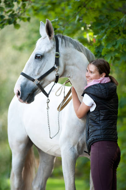 istock Young cheerful lady coach with her favorite white horse 1172807311