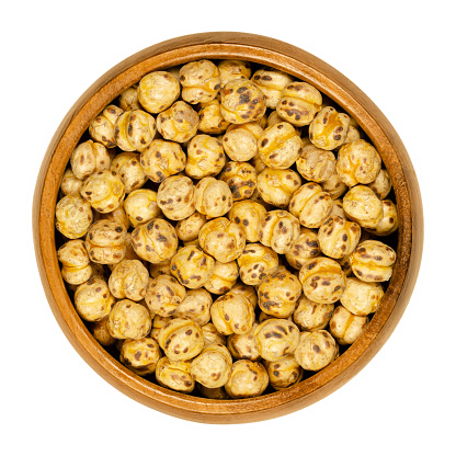 Roasted yellow chickpeas in wooden bowl. Crispy snack, vegan, high protein source, made of cooked chick peas. Isolated macro food photo, closeup, from above, on white background.