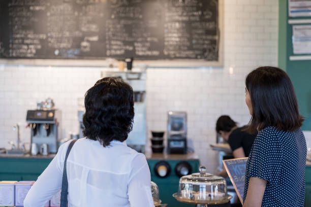 istock Rear view mother and daughter choosing from cafe menu 1172810425