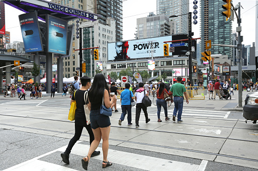 Toronto, Canada - August 18, 2019: Pedestrians walk to Yonge-Dundas Square in downtown Toronto on a summer afternoon. Commercial signs surround this popular venue for performances and festivals.