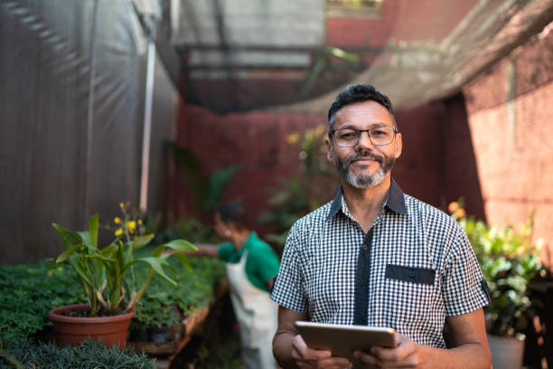 ritratto di fioraio che usa il tablet presso il negozio di fiori per piccole imprese - fioraio negoziante foto e immagini stock