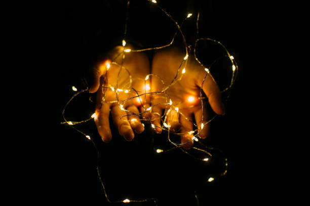 istock Christmas lights with warm shining in female hands. 1172823651